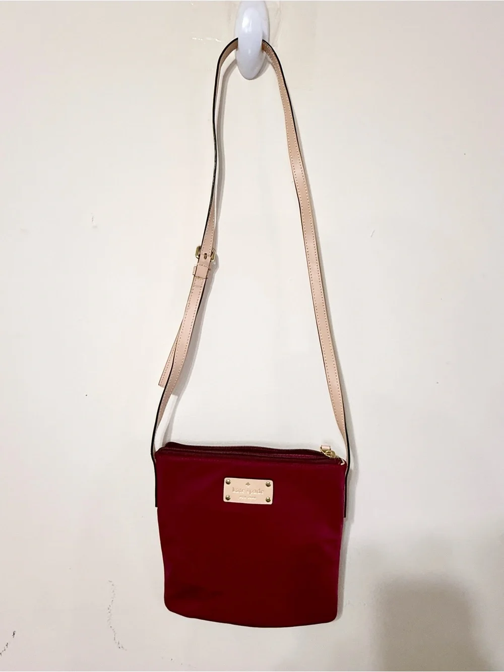 kate spade burgundy crossbody with beige strap and gold plaque